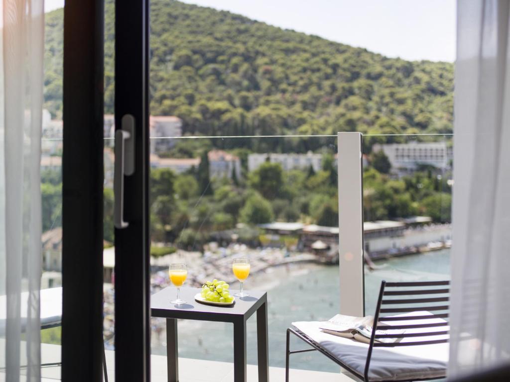 a balcony with a table and two glasses of wine at Hotel Kompas in Dubrovnik