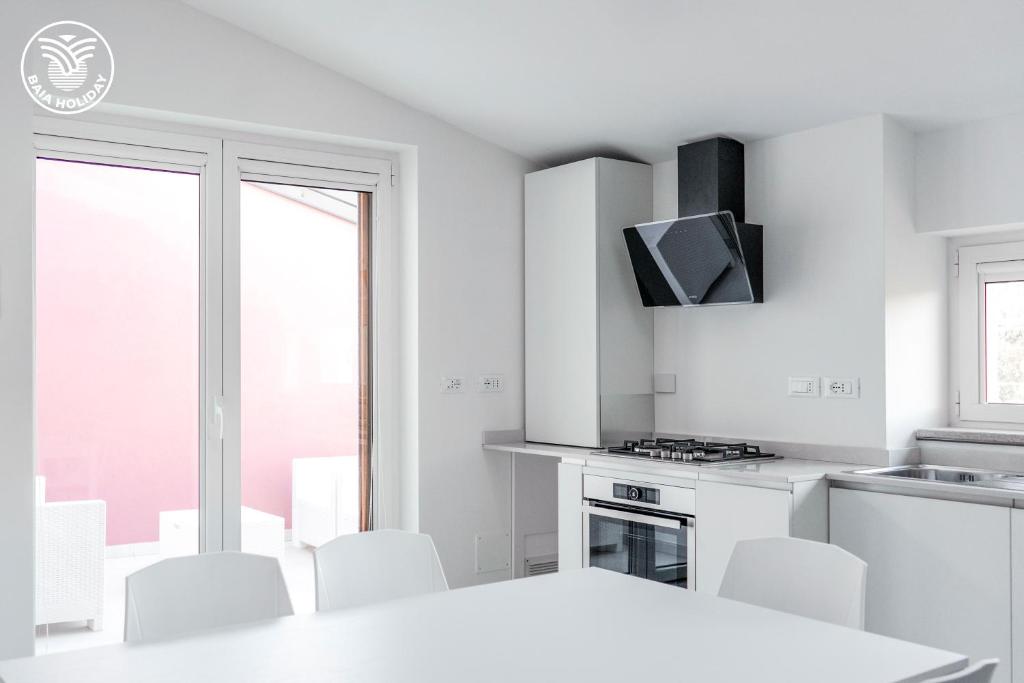 a white kitchen with a white table and white chairs at RESIDENCE BAIA RILKE in Sistiana