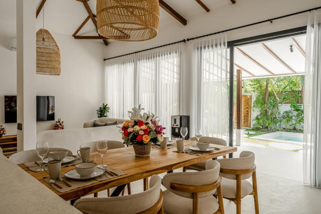 a dining room with a wooden table and chairs at Berapi Villa by EVDEkimi - Stylish Ubud Villa with Pool, Terrace, Kitchen & Concierge Service in Ubud