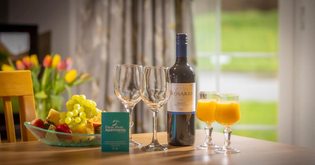 een fles wijn en twee glazen sinaasappelsap bij Killarney Flesk River Apartments in Killarney