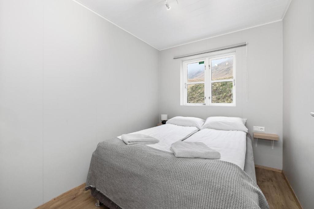a white bedroom with a bed and a window at Rauðafell apartment in Hvolsvöllur