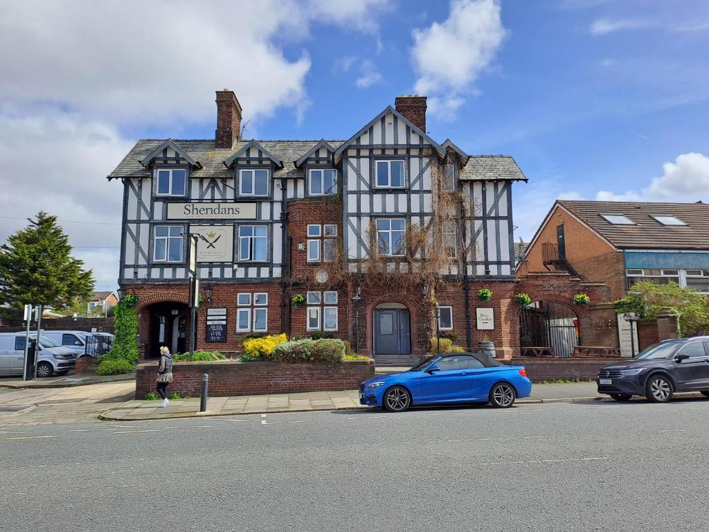 a blue car parked in front of a large house at Sheridans Budget Accomodation in Wallasey