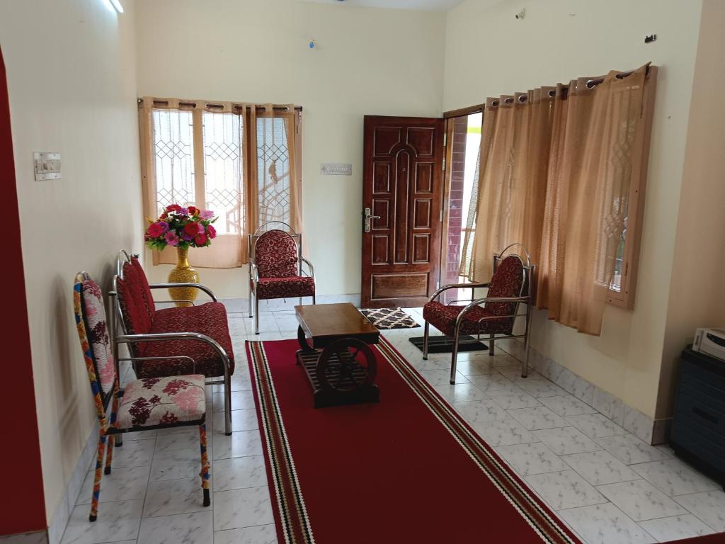 a living room with chairs and a red rug at Maria Vilas in Tirunelveli