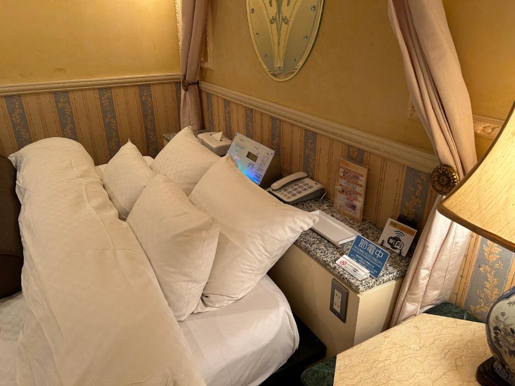 1 dormitorio con 1 cama con almohadas y teléfono en Hotel Grand Garden (Adult Only), en Yokohama