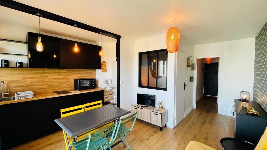 une cuisine et une salle à manger avec une table et un comptoir dans l'établissement Le Richelieu, charme face ocean, à Saint-Jean-de-Monts