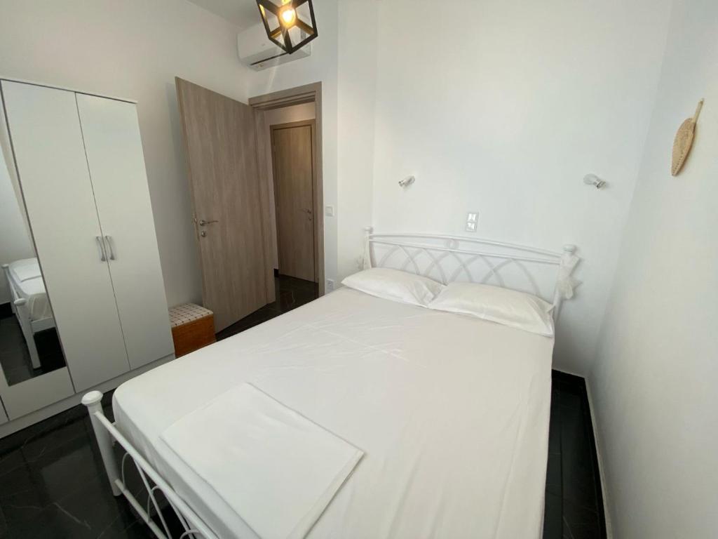 a bedroom with a white bed and a mirror at sun kiss houses in Áyios Spirídhon