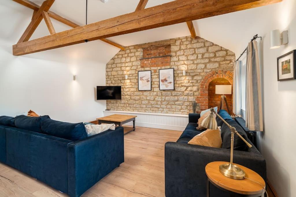 a living room with two blue couches and a stone wall at Blacksmiths cottage set on a peaceful farm in Buckinghamshire