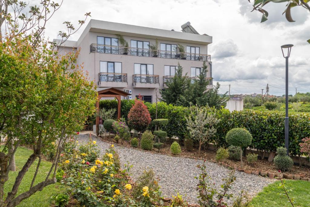 a white house with a garden in front of it at Te Aldo Hotel in Durrës