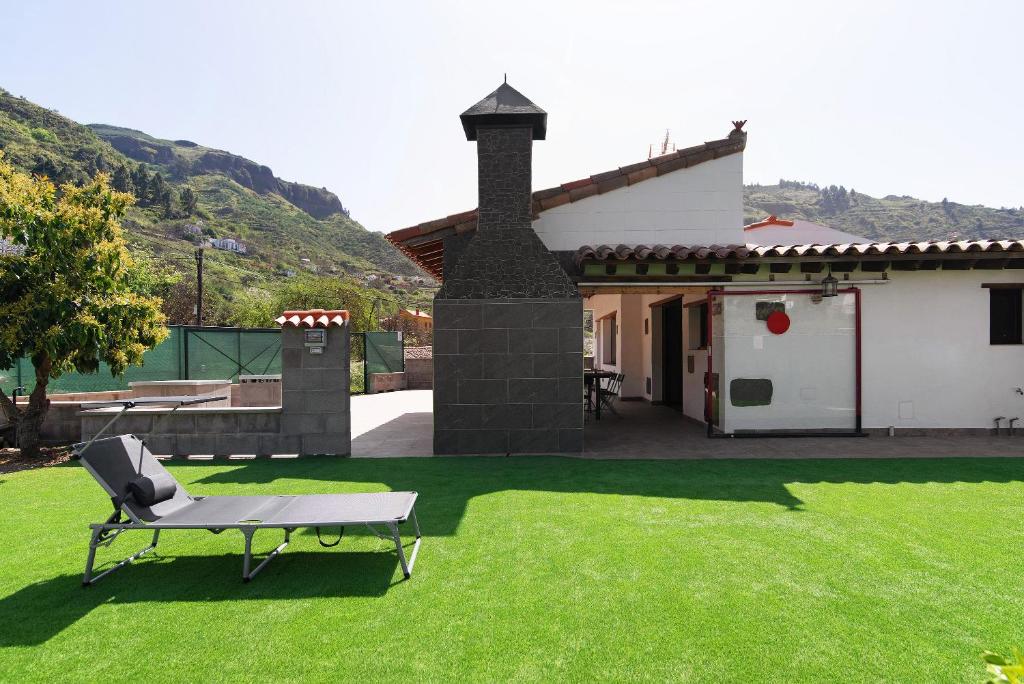 a lawn with a bench and a house at Villa Alma in Vega de San Mateo