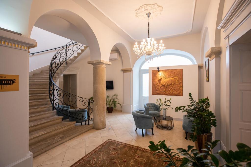 a hallway with a spiral staircase and a chandelier at Átrium Rooms & Café in Sopron