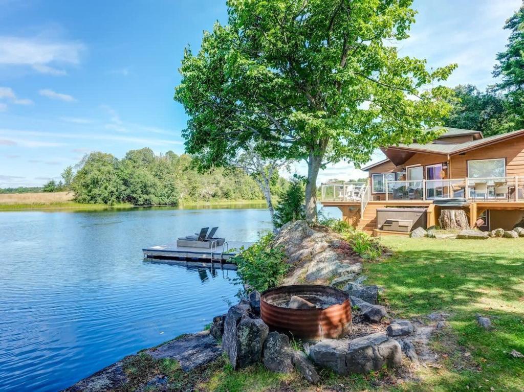 a house on a lake with a dock at Private waterfront cottage - hot tub & kayaks in Kingston