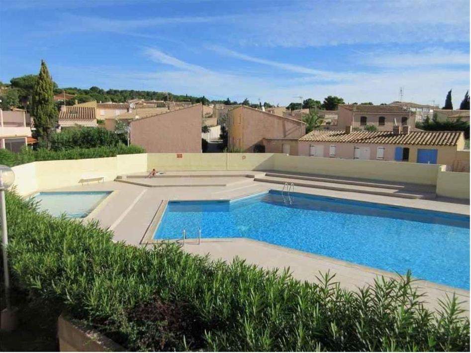 une grande piscine devant un immeuble dans l'établissement L'Agate, au Cap d'Agde