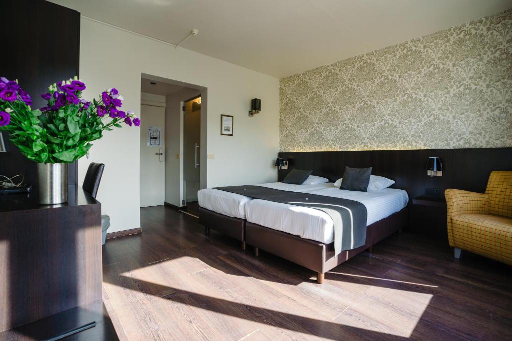 - une chambre avec un lit et un vase de fleurs violettes dans l'établissement Hôtel Ambassadeur, à Ostende