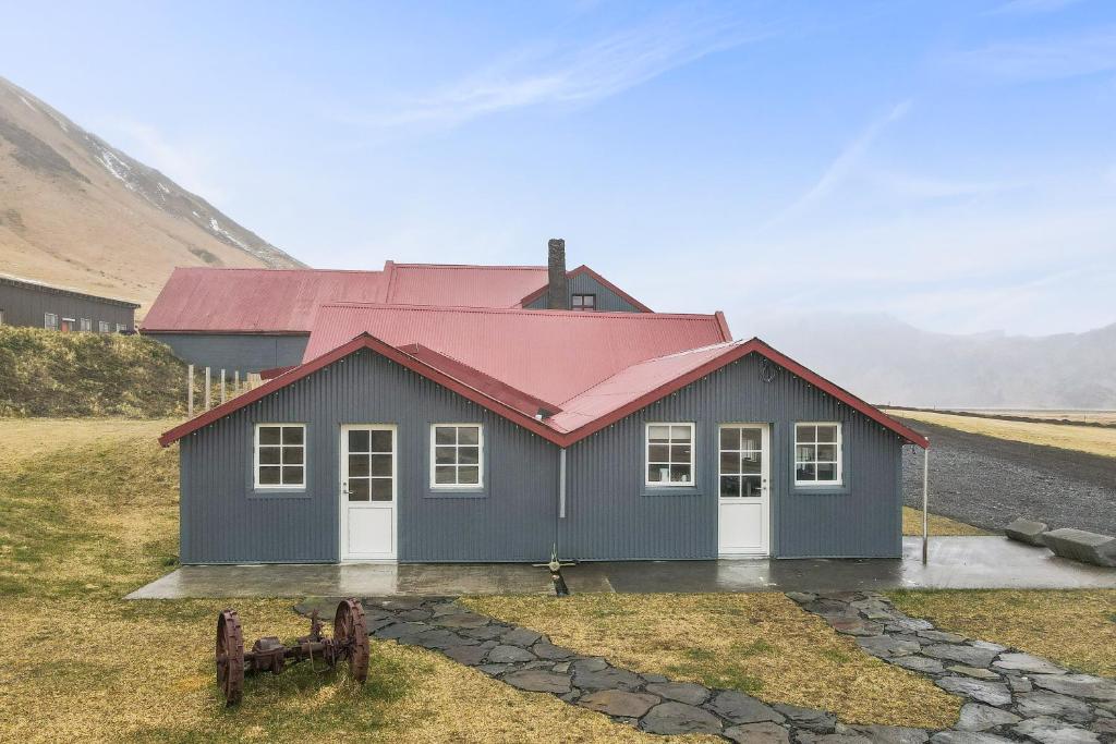una pequeña casa con techo rojo en un campo en Rauðafell ChickenCoop, en Skogar