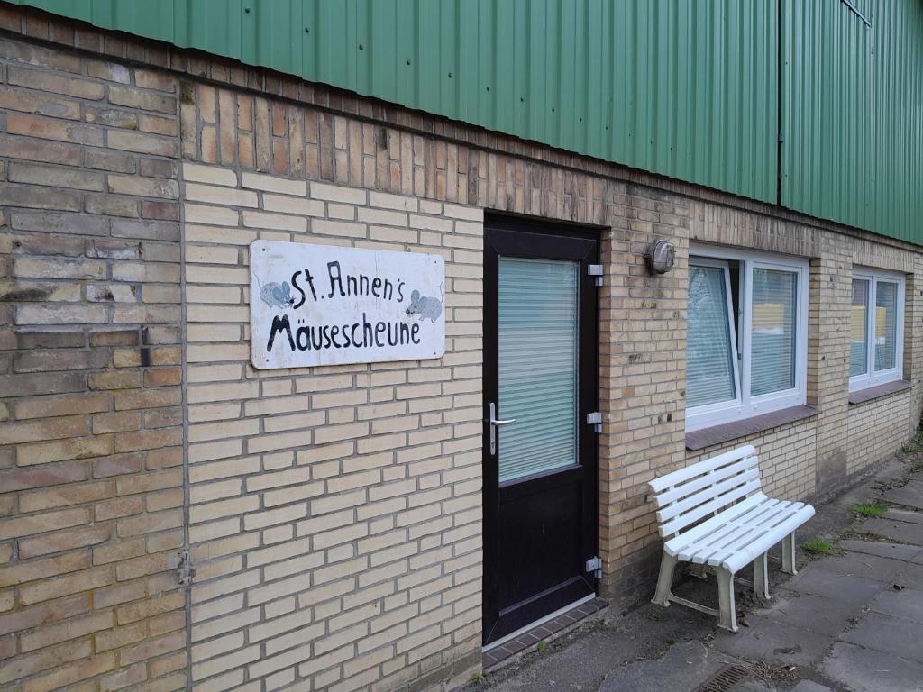 a brick building with a bench next to a door at MäuseScheune in Sankt Annen