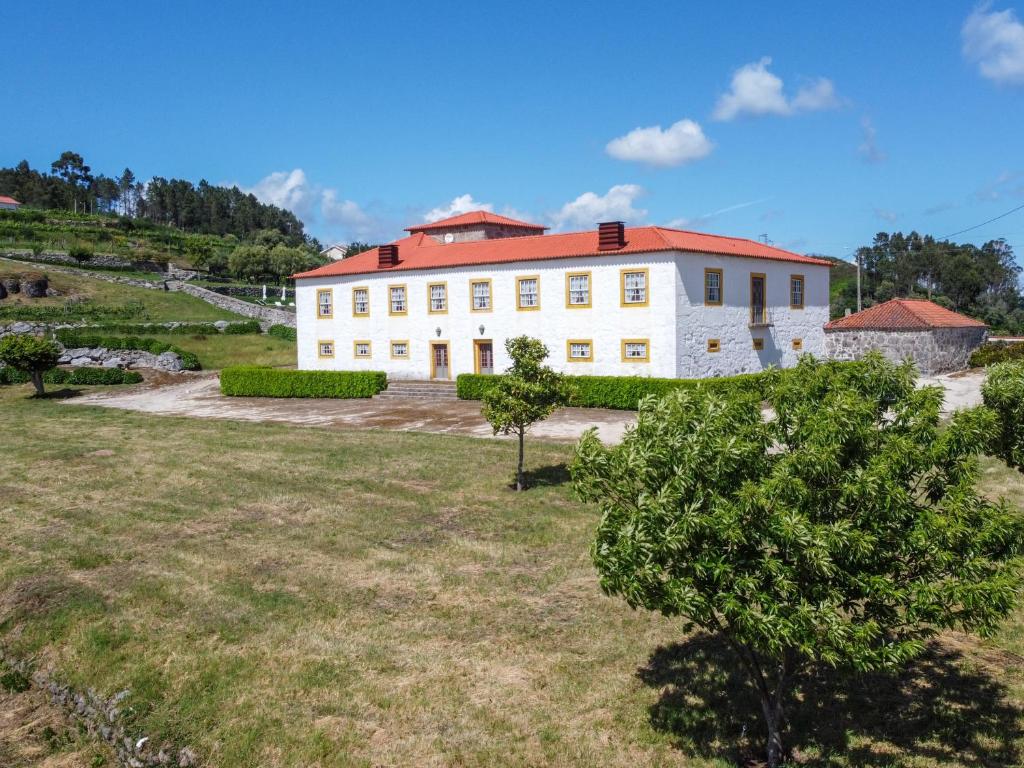 un grand bâtiment blanc avec un toit rouge dans l'établissement Casa da Portela de Sampriz, à Ponte da Barca