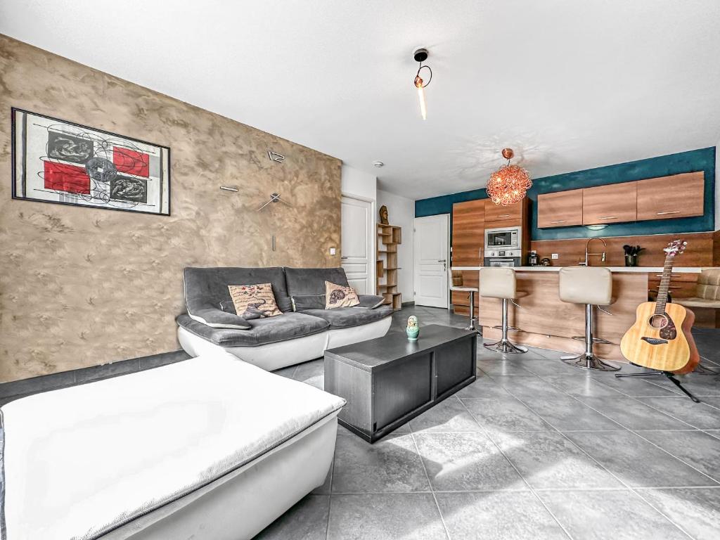 een woonkamer met een bank, een tafel en een gitaar bij Homey Melody - Proche Centre, Parking, Wifi, Terrace in Annemasse