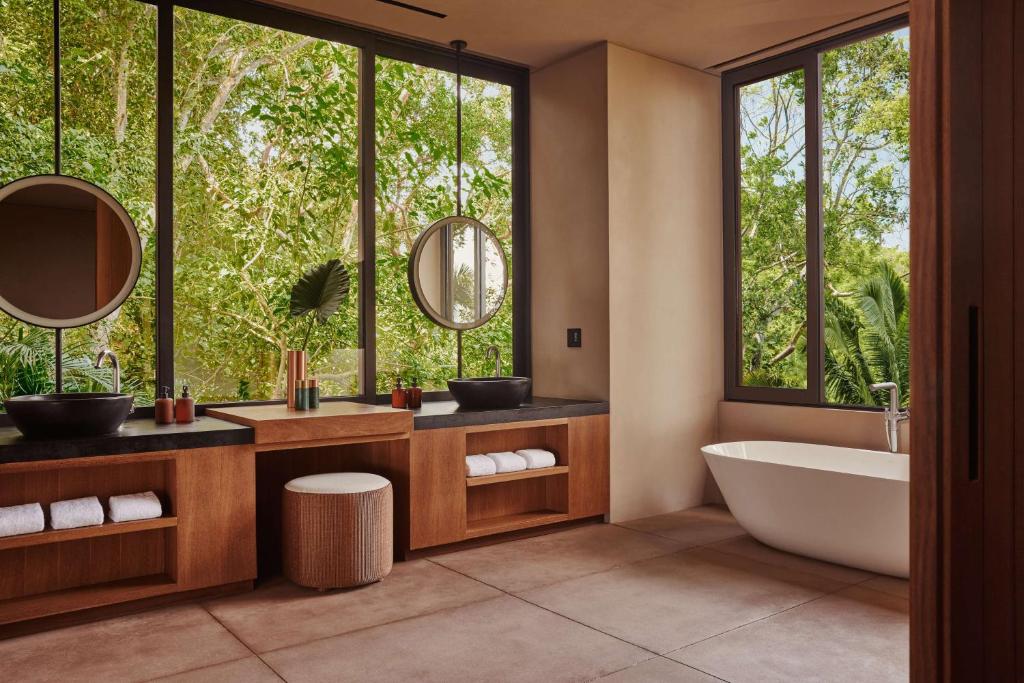 a bathroom with a tub and two sinks and a large window at One&Only Mandarina in Lo de Marcos