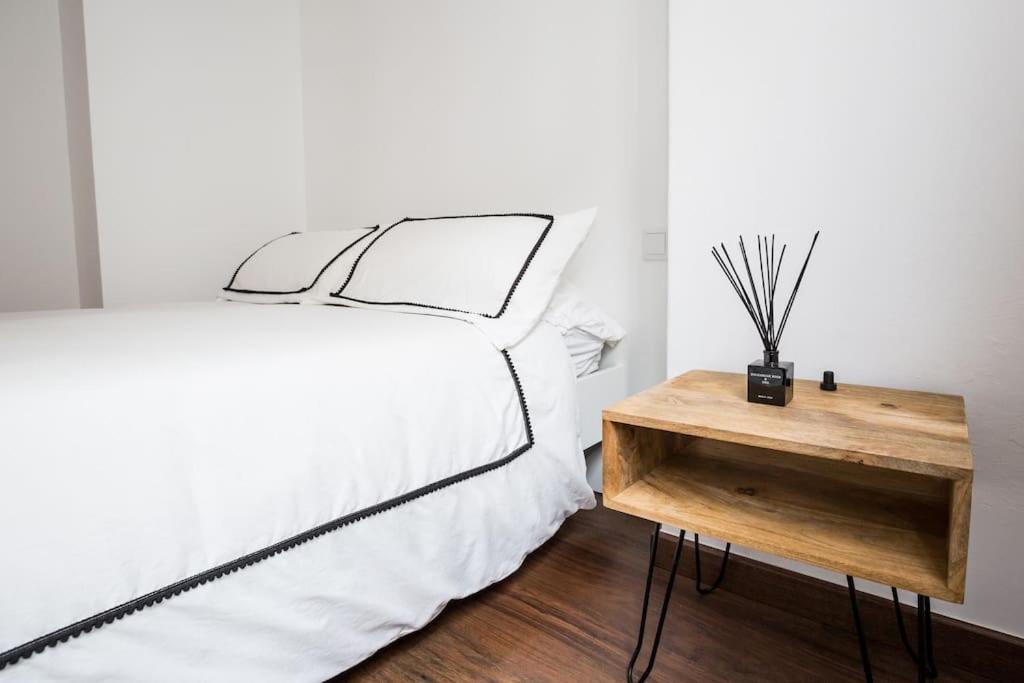 1 dormitorio con cama blanca y mesa de madera en Joya en el corazón de Ribeira, en Ribeira