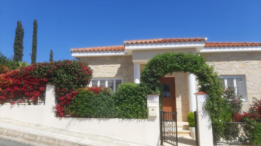a white house with flowers on a wall at Villa Best Holiday Sea View Private Pool near Coral Bay with Garden and BBQ in Peyia