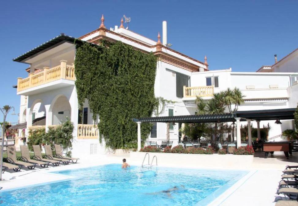 a person in a swimming pool next to a house at Hotel Al Sur De Chipiona by YouRoom in Chipiona