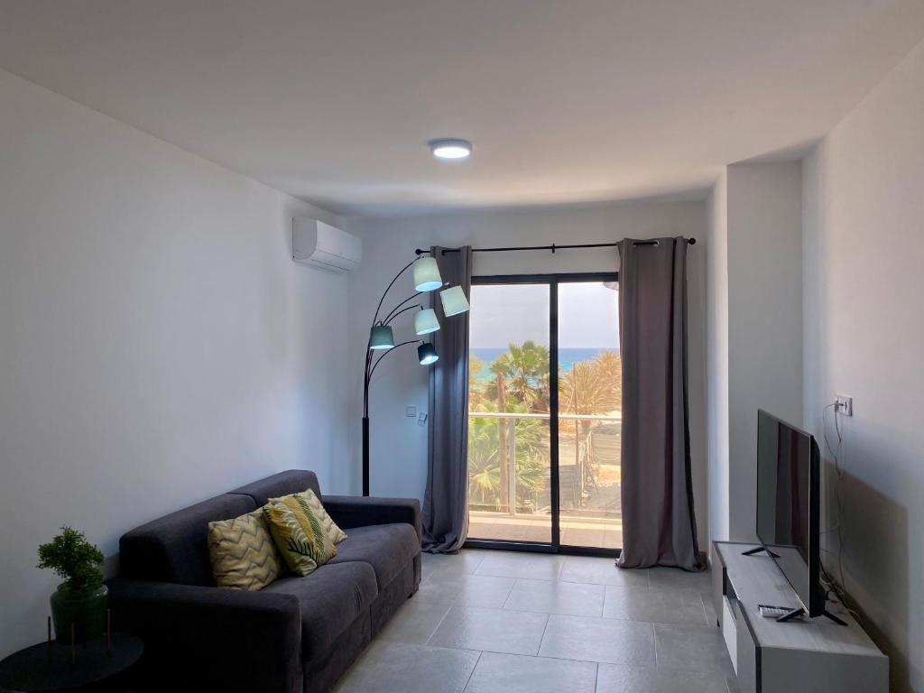 sala de estar con sofá y puerta corredera de cristal en Atlantic Sal Design Apartments en Santa María