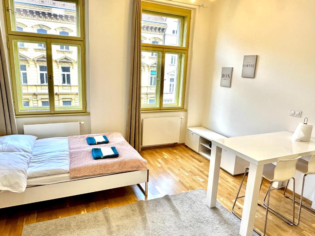 Schlafzimmer mit einem Bett, einem Schreibtisch und Fenstern in der Unterkunft LEX apartments Prague in Prag