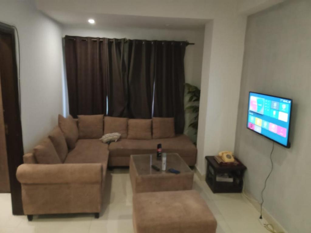 uma sala de estar com um sofá castanho e uma televisão em 2 bedroom family apartments em Islamabad