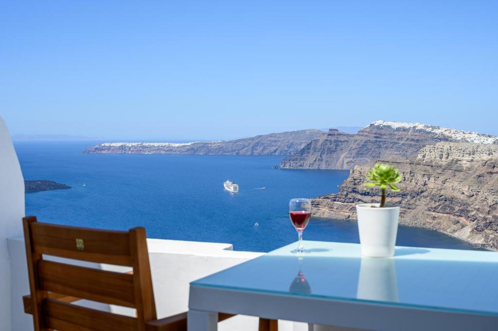 a table with a glass of wine and a view of the ocean at Spectacular view Caldera St Μ in Megalochori