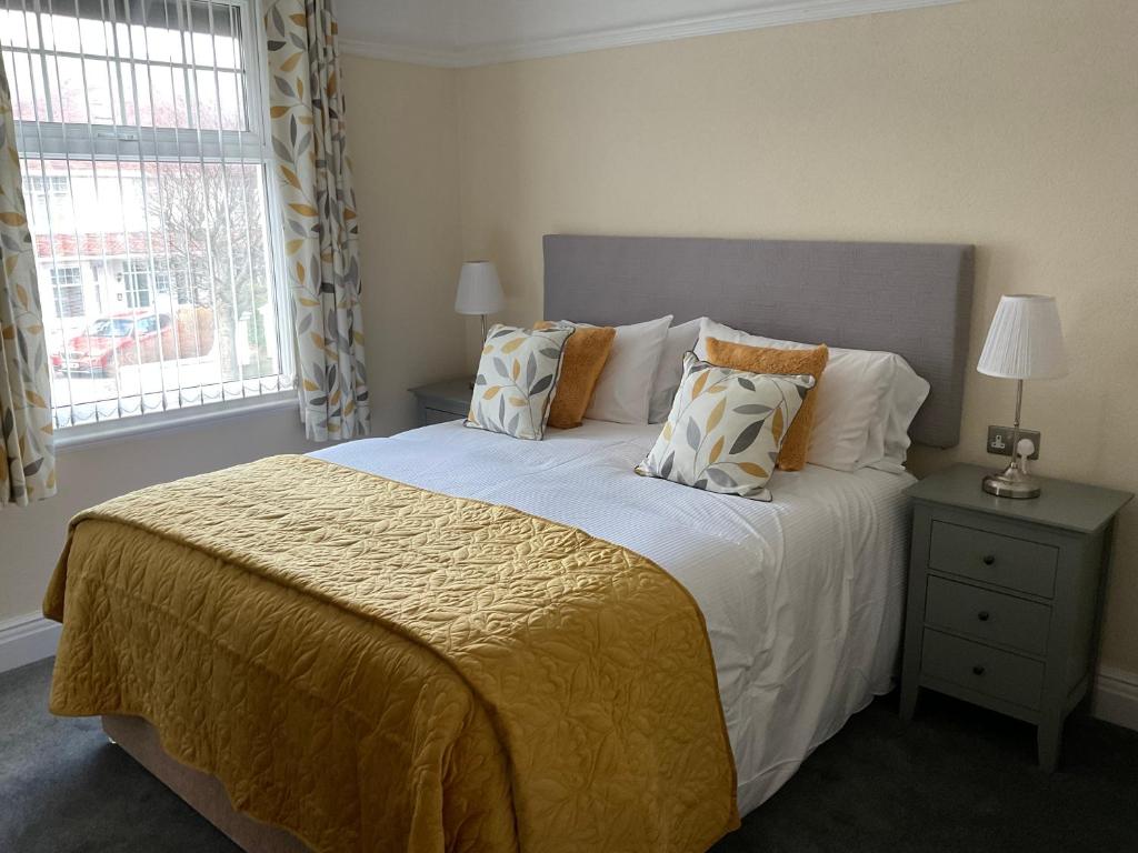 um quarto com uma cama grande com almofadas e uma janela em Cornerways Llandudno em Llandudno