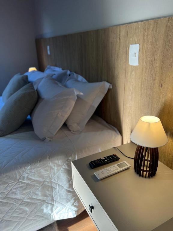 Una cama con almohadas azules y una mesa con lámpara. en Terras Claras Pousada e Lazer, en Alfredo Chaves