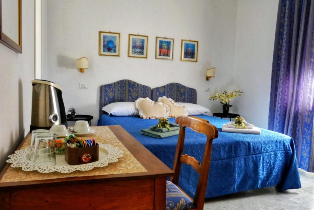 Un dormitorio con una cama azul y una mesa en B&B Myosotis, en Pisa