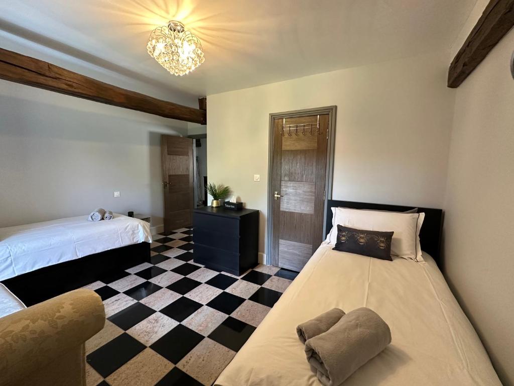 a bedroom with two beds and a checkered floor at Chambres d'hôtes du Vigeant in Le Vigeant
