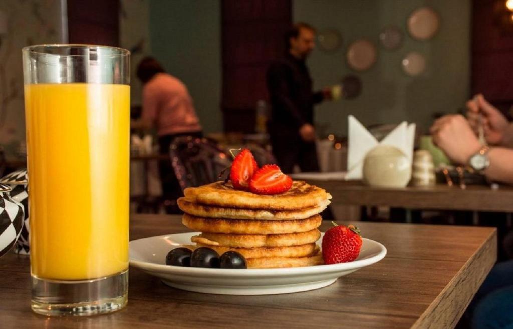 a plate of pancakes and strawberries next to a glass of orange juice at Hazz Palace Hotel in Baku