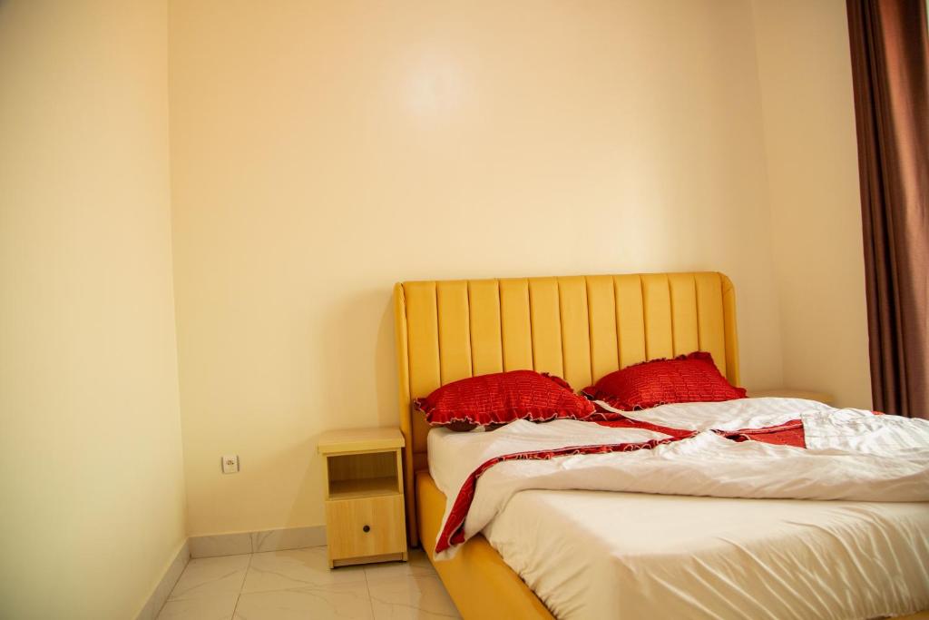 キガリにあるTWINKLE Appartmentsのベッドルーム1室(赤い枕のベッド1台付)