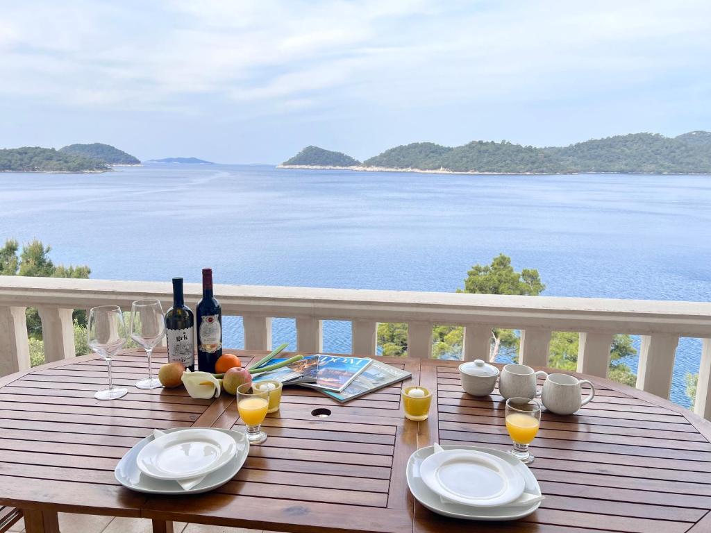 una mesa de madera con botellas de vino y copas en el balcón en Terrace apartments, en Ubli