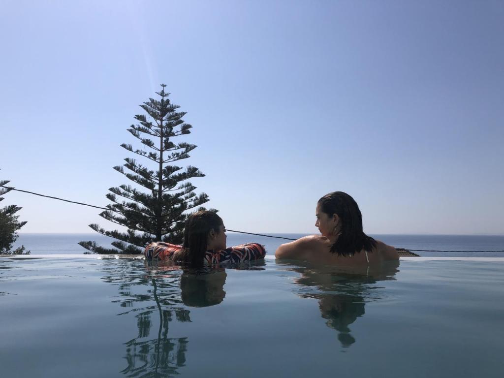 two women swimming in the water next to a tree at Anassa Villas in Vrachos