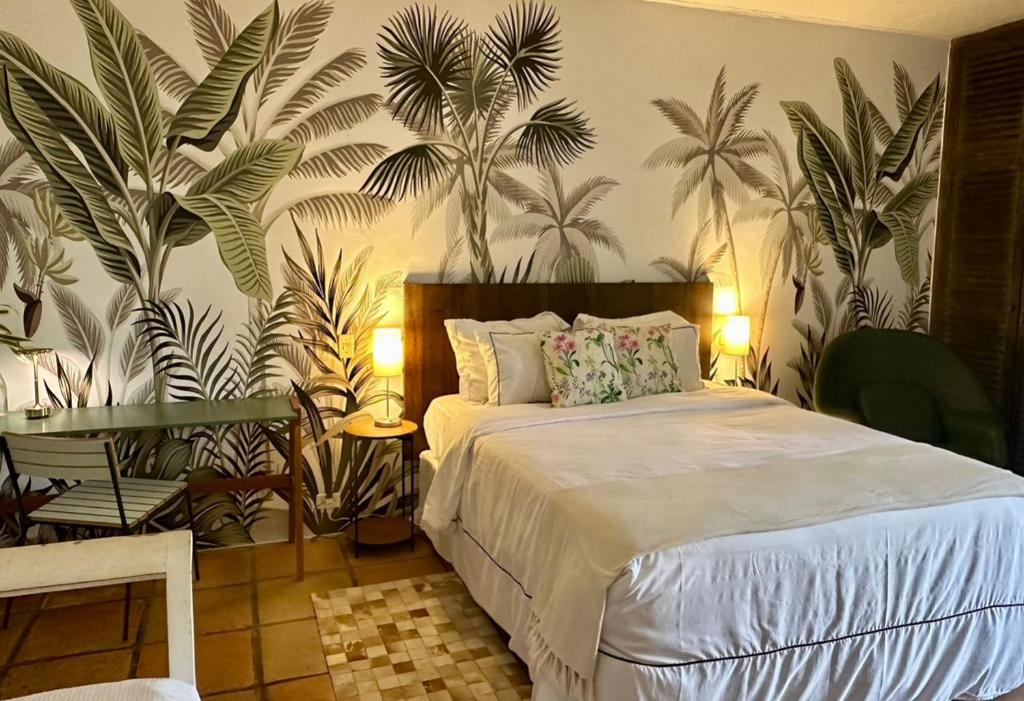 a bedroom with a bed and plants on the wall at Pousada Casa Paradiso Guarujá in Guarujá