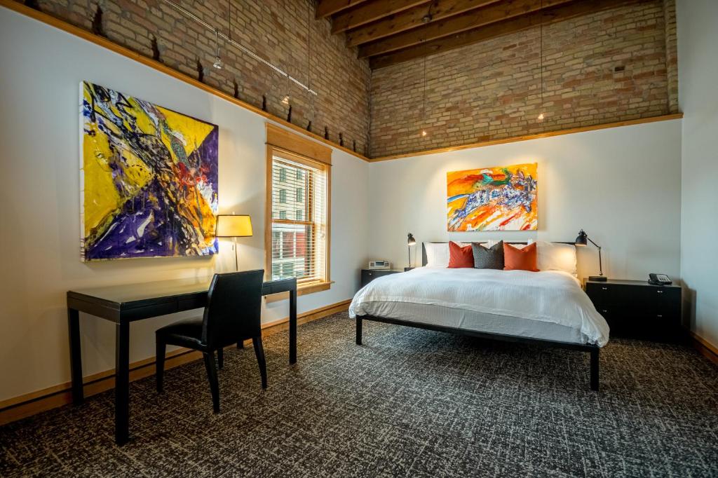 um quarto com uma cama, uma secretária e pinturas em Hotel Donaldson em Fargo