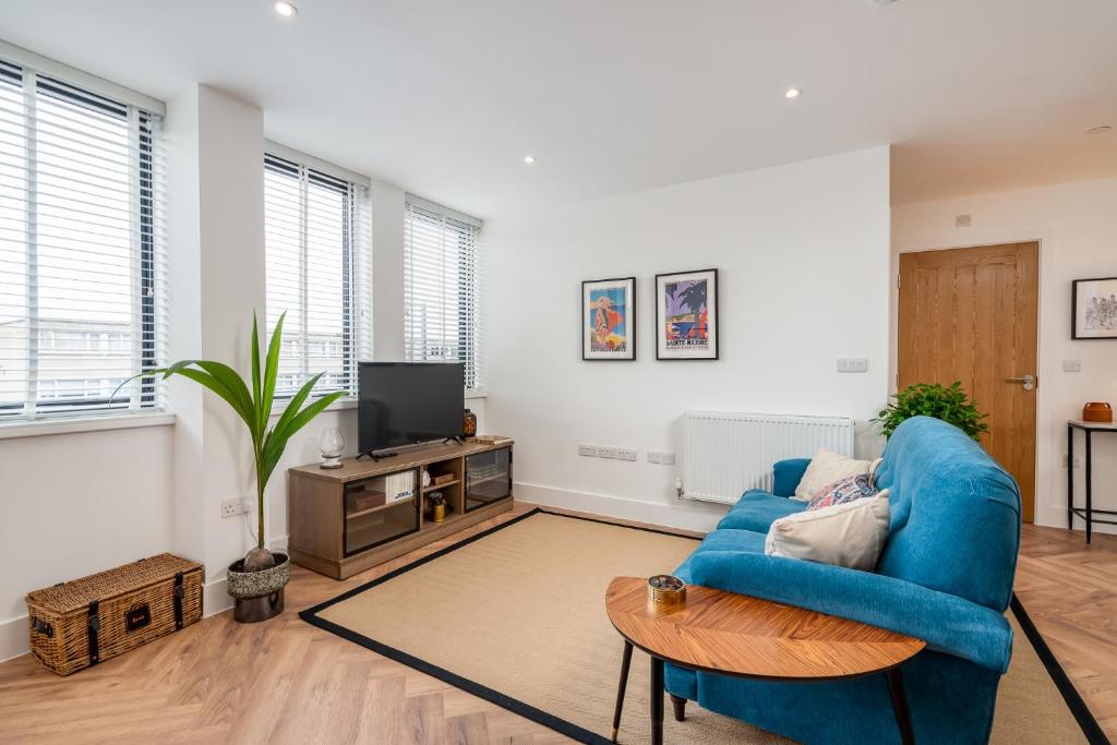 a living room with a blue couch and a tv at Stylish Spacious Apartment in Central Windsor in Windsor