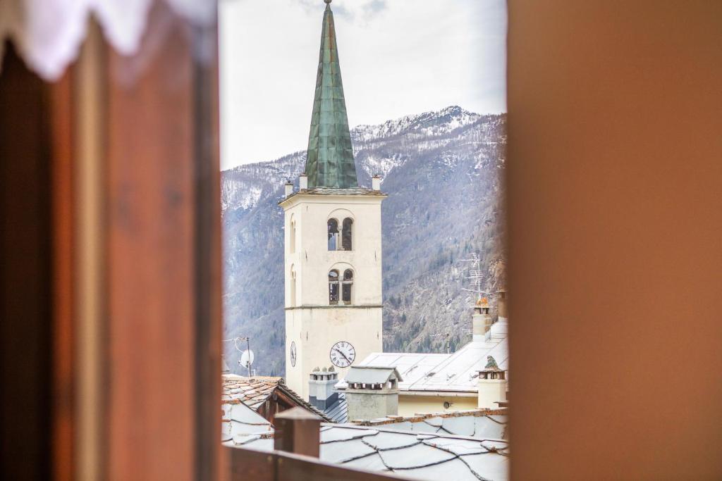 a church with a steeple is seen through a window at Valtournenche, monolocale in centro in Valtournenche