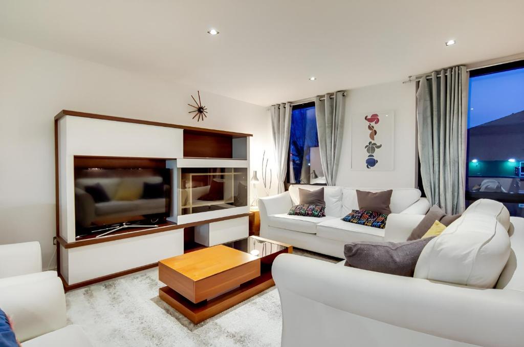a living room with white furniture and a large tv at Still Life Warren Street in London