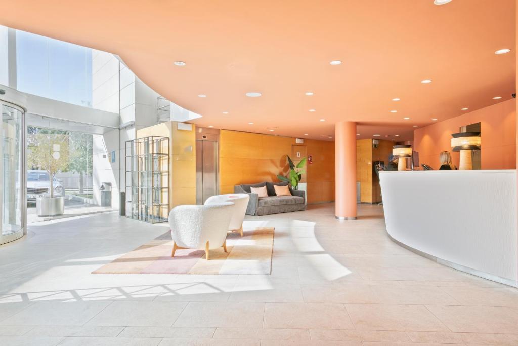 a lobby with white chairs and a couch at Hotel Sant Just in Sant Just Desvern