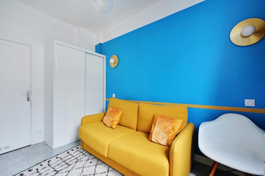 a yellow couch in a room with a blue wall at Cosy studio - Belleville in Paris