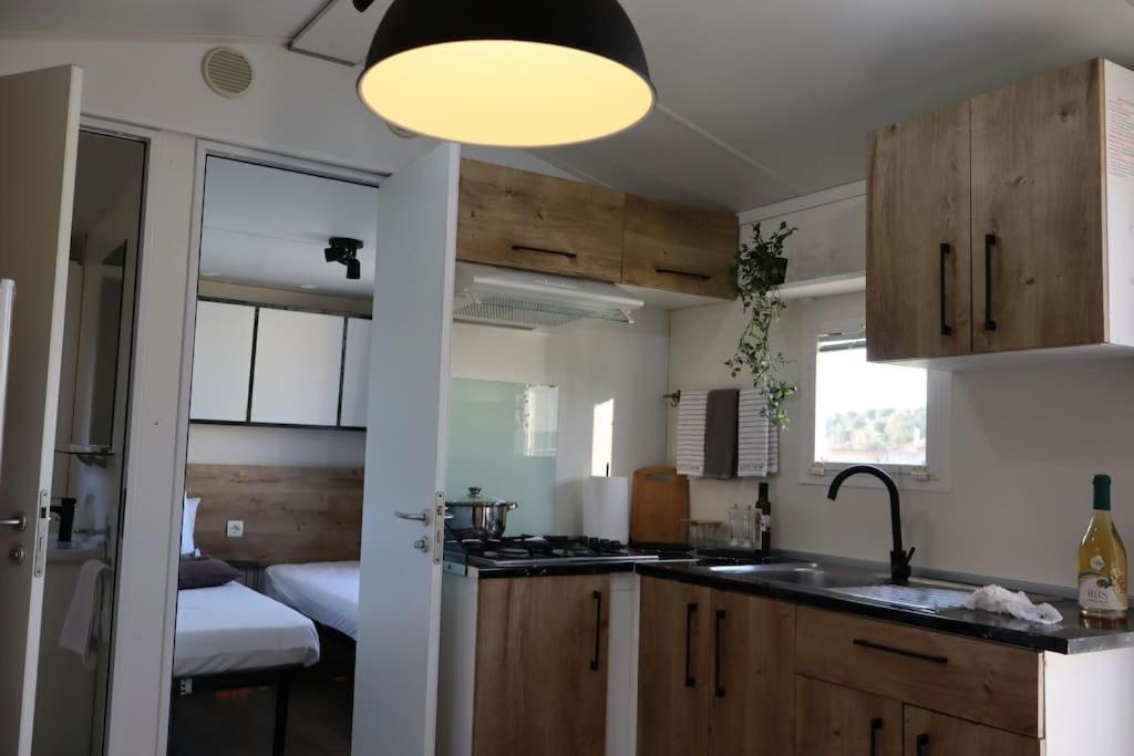 cocina con armarios de madera, fregadero y lámpara en House on wheels en Karterólion