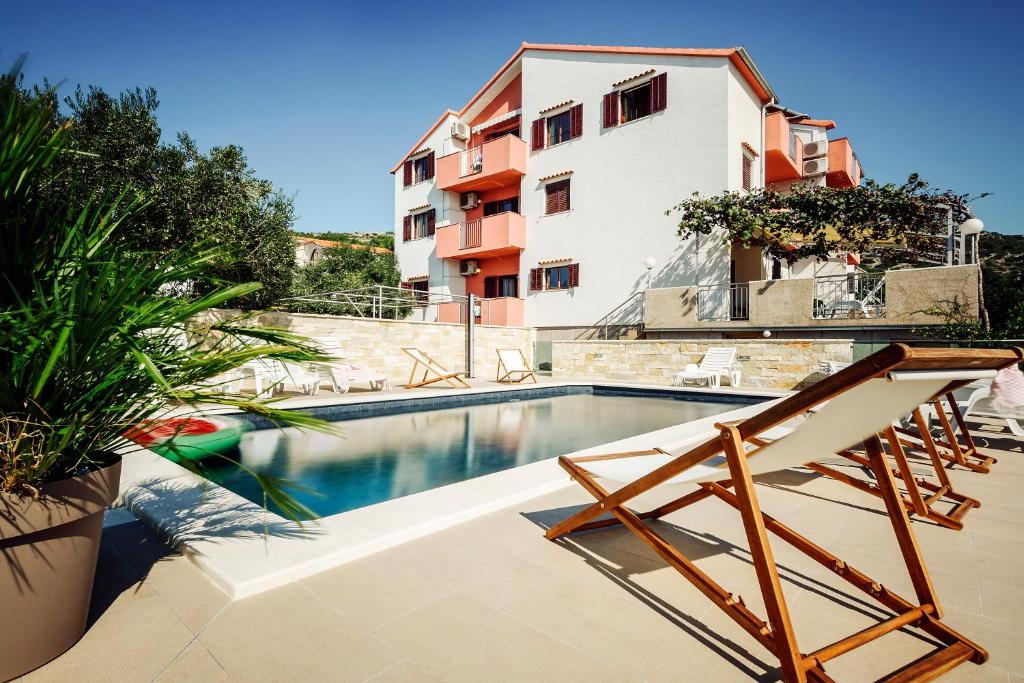 a swimming pool with a chair and a building at Apartments Martina 2 in Primošten