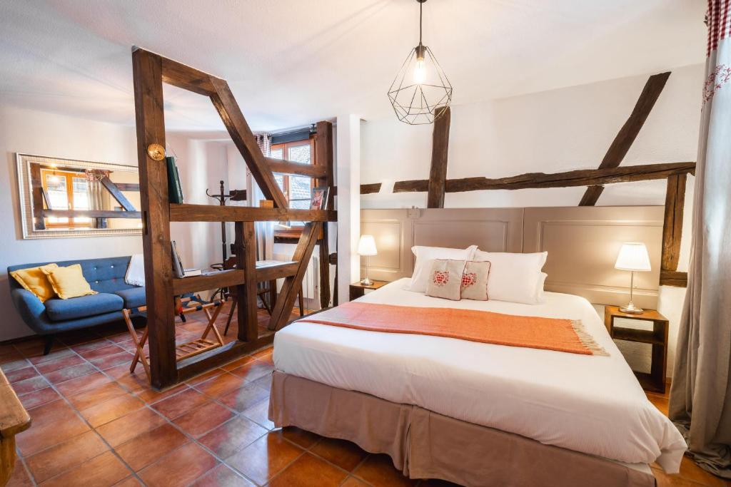 a bedroom with a large bed and a chair at Les Suites - La Cour St Fulrad in Saint-Hippolyte