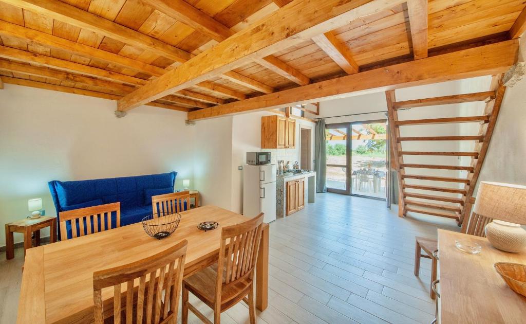 Il comprend une cuisine et une salle à manger avec une table et des chaises en bois. dans l'établissement Lofts with private outdoor area and swimming-pool in Badesi, à Badesi