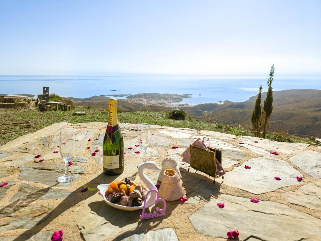 una mesa con una botella de vino y un bol de fruta en El paraíso de Cadaqués IMMO365, en Cadaqués