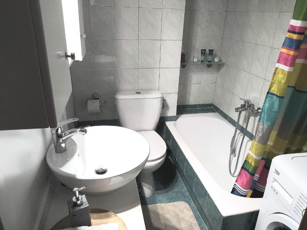 ein Badezimmer mit einem WC, einem Waschbecken und einer Badewanne in der Unterkunft Lenia's seaside apartment in Faraí